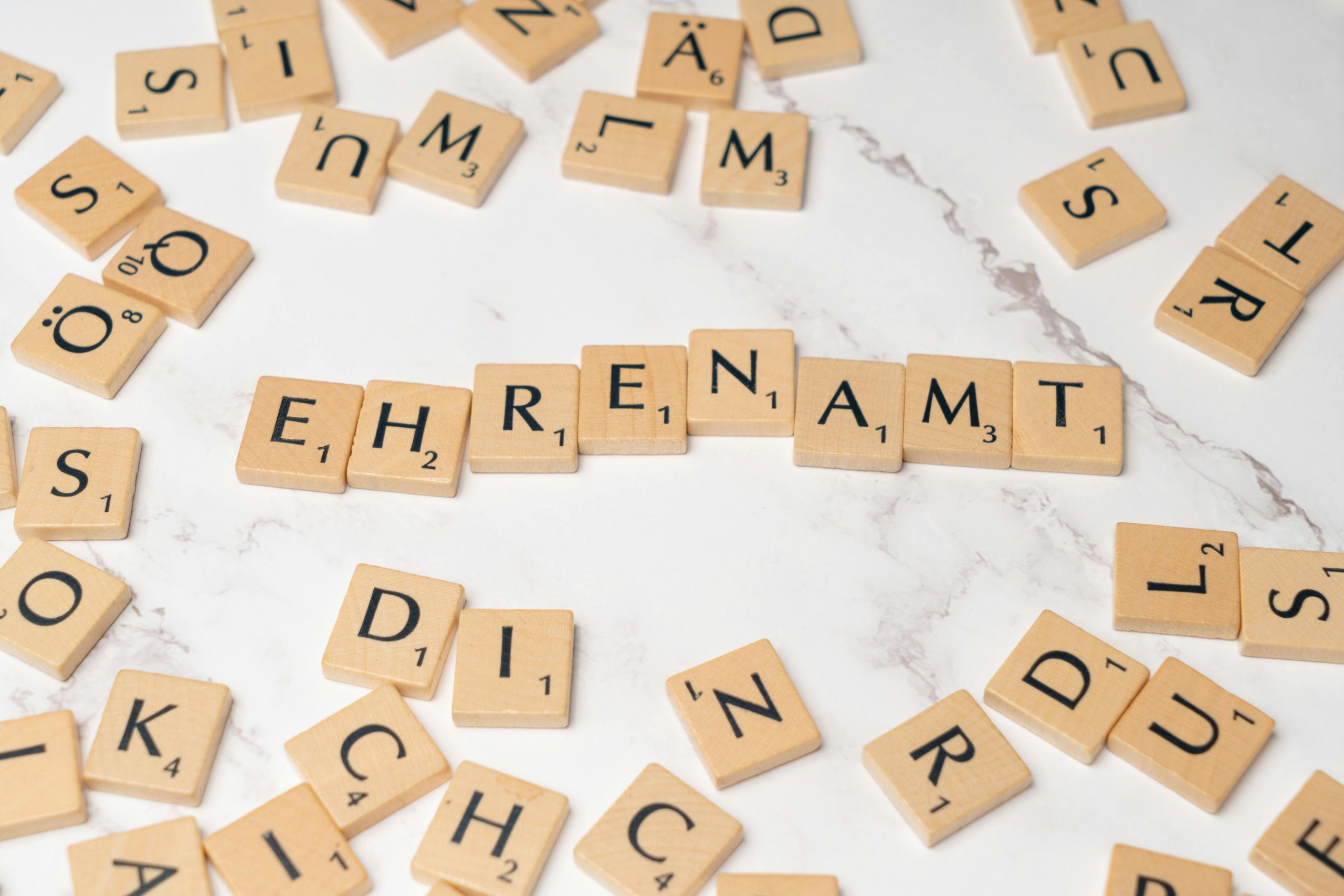 Close-up of Scrabble tiles spelling 'Ehrenamt', symbolizing volunteerism and community service.